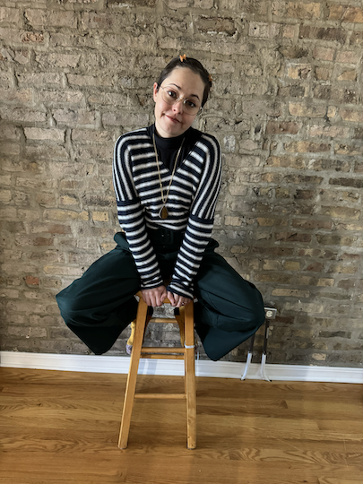 Lauren Plug, founder of Copy by LP in a blue and white striped sweater sitting on a stool